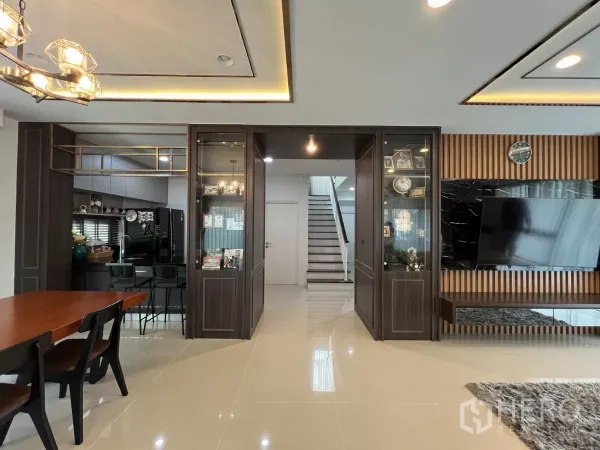 Detached House for rent or sale in Bang Kapi, Bangkok - Open-plan dining to living room with built-in cabinets and staircase at center.