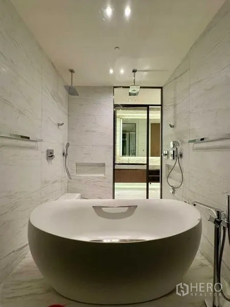 Condominium for rent or sale - Spa-style bathroom with freestanding oval bathtub, marble walls and rain shower.
