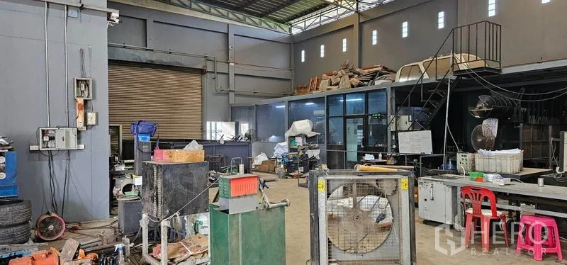 Warehouse for rent in Bang Kruai, Nonthaburi - Warehouse interior showing high ceiling, roller shutter door and workshop area.