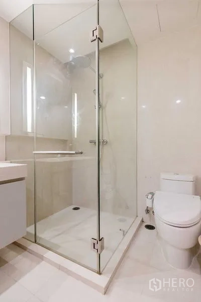 Condominium for rent - Bathroom featuring a clear glass shower enclosure and toilet.