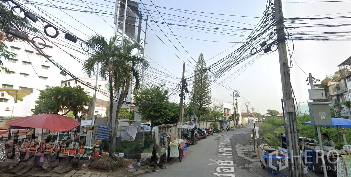 Land for sale in Phasi Charoen, Bangkok - Local access road with overhead utilities, street vendors and greenery near the Bang Wa area.