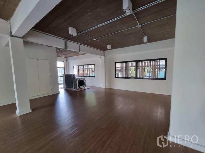 带办公室的家 出租或出售在Phaya Thai, Bangkok - 开放式办公空间，木质地板、白色墙面与外露管线天花，配大窗户。