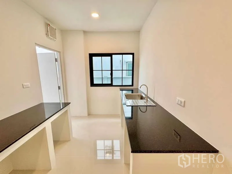 Detached House for sale in Bang Phli, Samut Prakan - Bright separate kitchen with black granite countertops, sink and window.