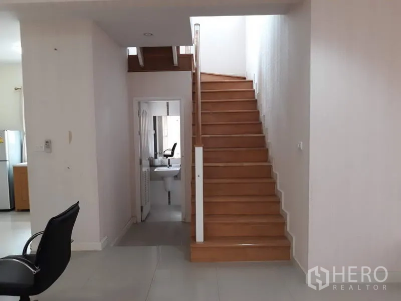 Detached House for rent in Suan Luang, Bangkok - Wood staircase and hallway with a view to the ground-floor bathroom
