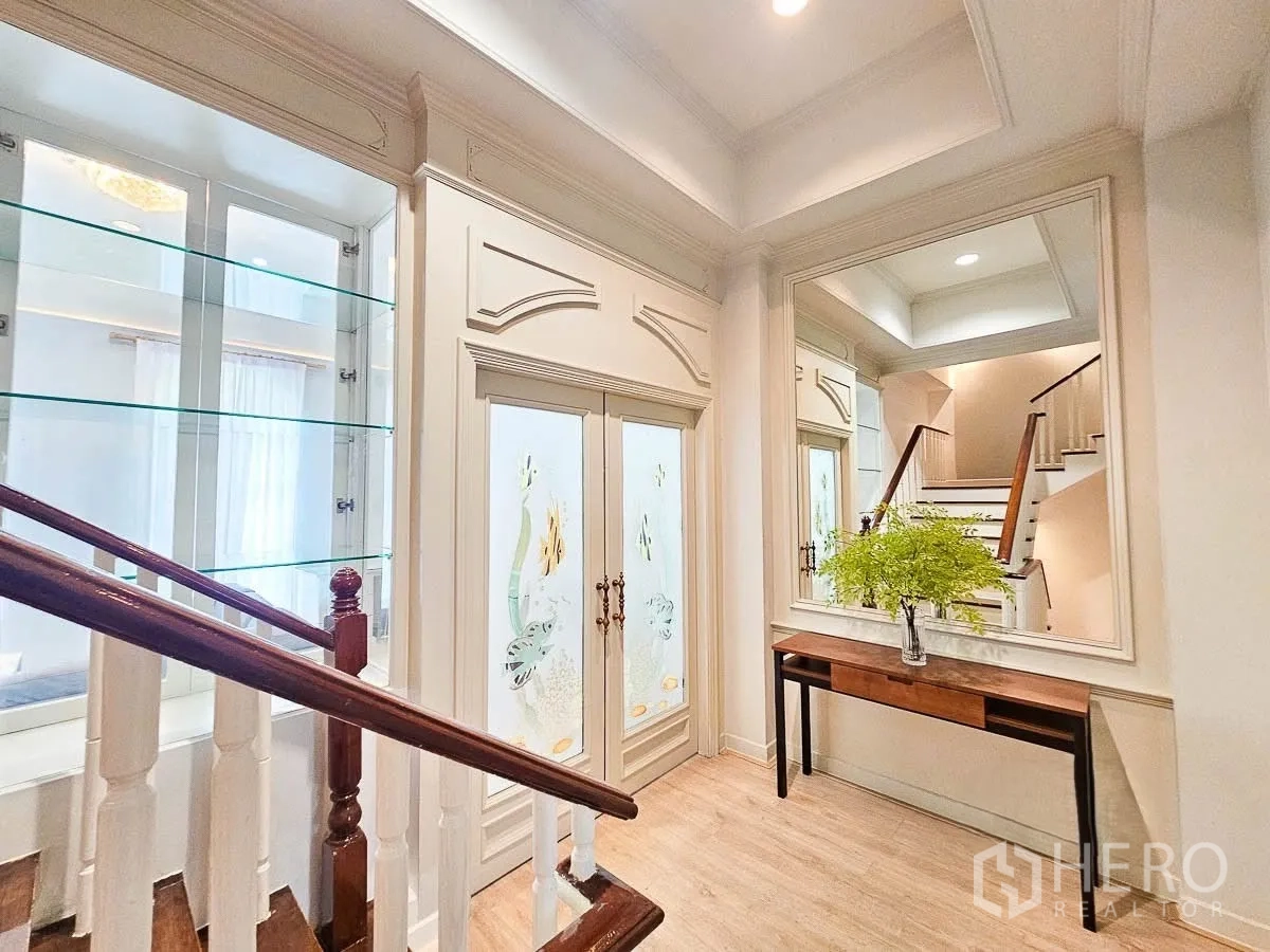联排别墅 for rent in Yan Nawa, Bangkok - 玄关走廊，楼梯、大镜面与玻璃展示柜，嵌灯照明。