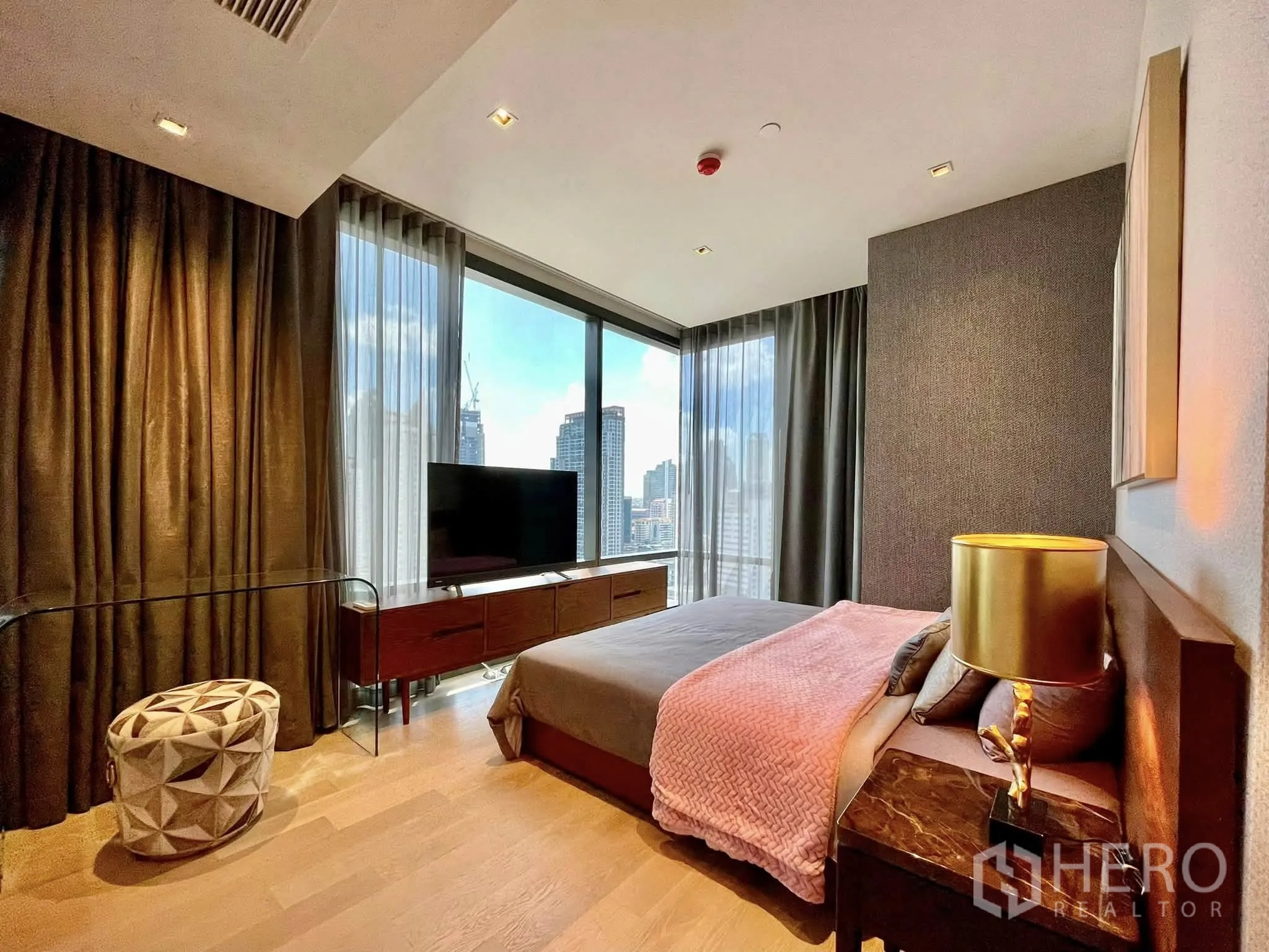Condominium for rent in Bang Rak, Bangkok - Corner bedroom with panoramic windows, TV console and city skyline view.
