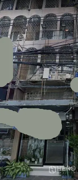 อาคารพาณิชย์ ให้เช่าในWatthana, Bangkok - ด้านหน้าอาคารพาณิชย์หลายชั้นย่านทองหล่อ มีซุ้มหน้าต่างเหล็กดัด ประตูกระจกหน้าร้าน กระถางต้นไม้ และสายสาธารณูปโภคเหนือถนน