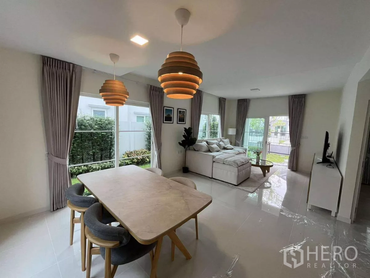 Detached House for rent in Bang Phli, Samut Prakan - Open-plan dining and living area with pendant lights and greenery outside.