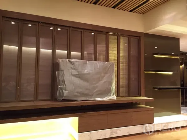 Condominium for rent in Yan Nawa, Bangkok - Custom TV wall with warm wood paneling and underlit shelving in the living room.