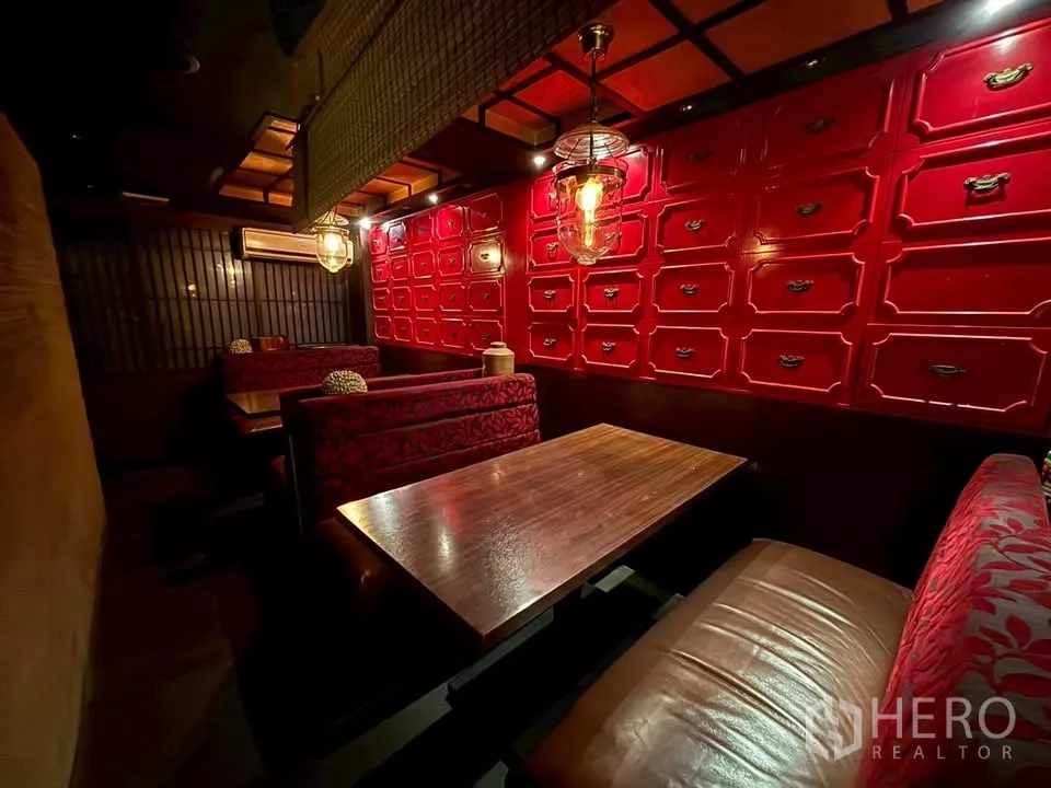 店屋 出租在Watthana, Bangkok - 温馨卡座用餐区，木桌、红色柜墙和吊灯。