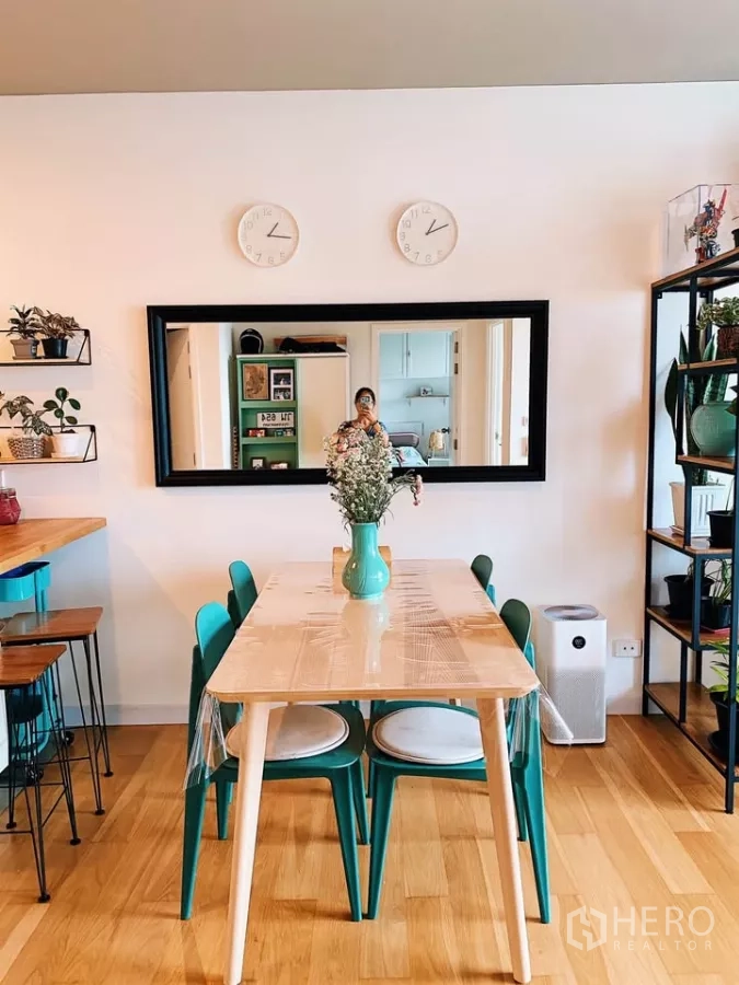 Condominium for rent in Watthana, Bangkok - Minimal dining table under a long wall mirror with twin clocks above.