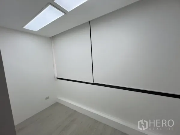 Office Space for rent in Khlong Toei, Bangkok - Compact private room with white walls, LED ceiling panels and a window covered by a roller blind.