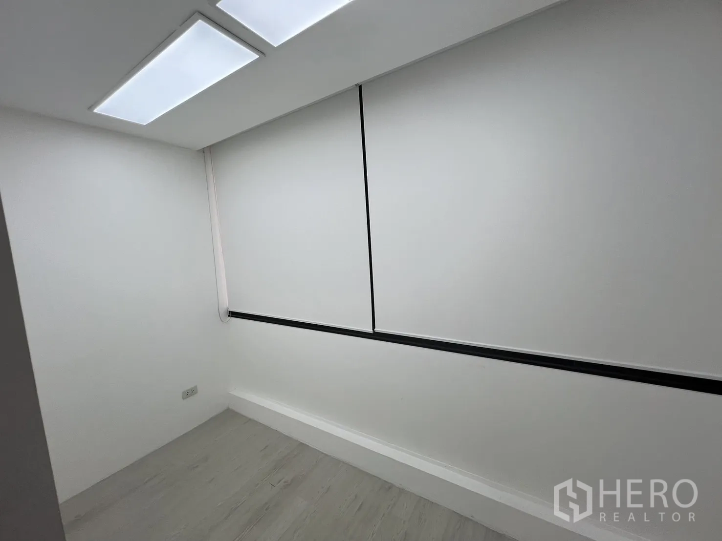 Office Space for rent in Khlong Toei, Bangkok - Compact private room with white walls, LED ceiling panels and a window covered by a roller blind.