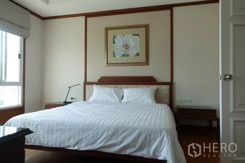Condominium for rent in Khlong Toei, Bangkok - Master bedroom with king bed, bedside tables and floral artwork.