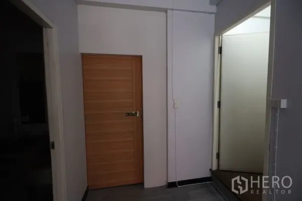 店屋 出租或出售在Watthana, Bangkok - 室内过道，木质门与白色门框，墙面简洁并有外露线管