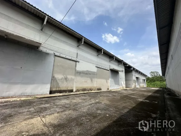 คลังสินค้า ให้เช่าในPhra Nakhon Si Ayutthaya - แนวโกดังหลายยูนิตพร้อมประตูบานเลื่อนและทางสัญจรคอนกรีต