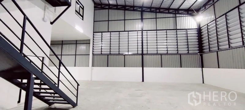 Warehouse for rent in Lam Luk Ka, Pathum Thani - Industrial interior with metal staircase and expansive concrete floor.