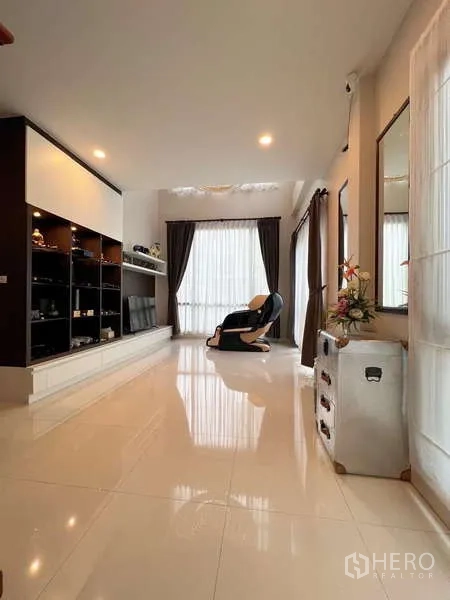 Detached House for sale in Prawet, Bangkok - Bright lounge with glossy tile floor, full-height curtains, and built-in display shelving.