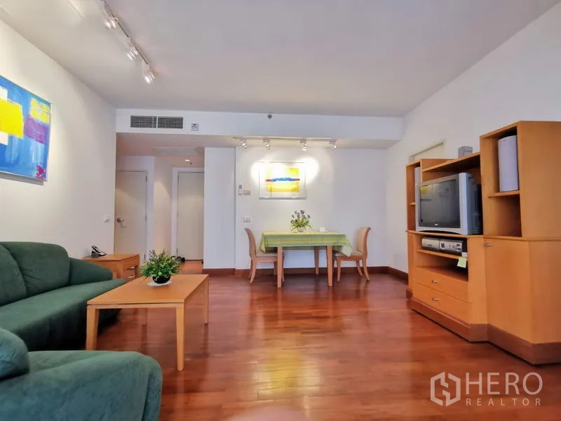 公寓 出租在Pathum Wan, Bangkok - 采光充足的客餐厅，木地板、绿色沙发、电视柜与轨道灯。