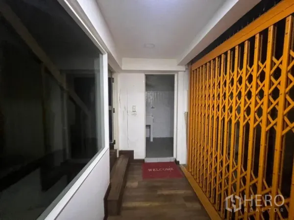 อาคารพาณิชย์ ให้เช่าหรือขายในWatthana, Bangkok - โถงภายในพร้อมประตูเหล็กยืดสีเหลือง ขั้นบันได และประตูห้องน้ำเล็ก ๆ.