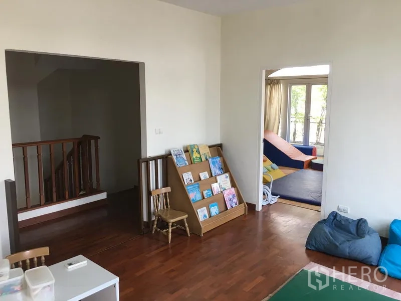 ทาวน์เฮาส์ ขายในHuai Khwang, Bangkok - ห้องครอบครัวพื้นไม้ ชั้นวางหนังสือ และห้องนอนติดระเบียงถัดไป