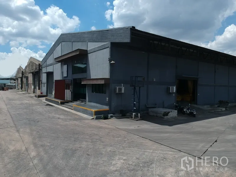 工厂 出租在Phra Pradaeng, Samut Prakan - 转角视角的成排仓库，多个出入口与宽大混凝土场地。