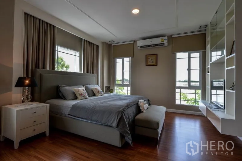 Detached House for sale in Bang Kapi, Bangkok - Spacious master bedroom with large windows, bedside tables and wood floors.