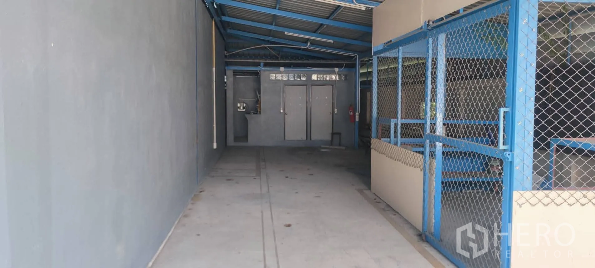Warehouse for sale in Thung Khru, Bangkok - Interior loading corridor with chain-link storage area and utility doors.