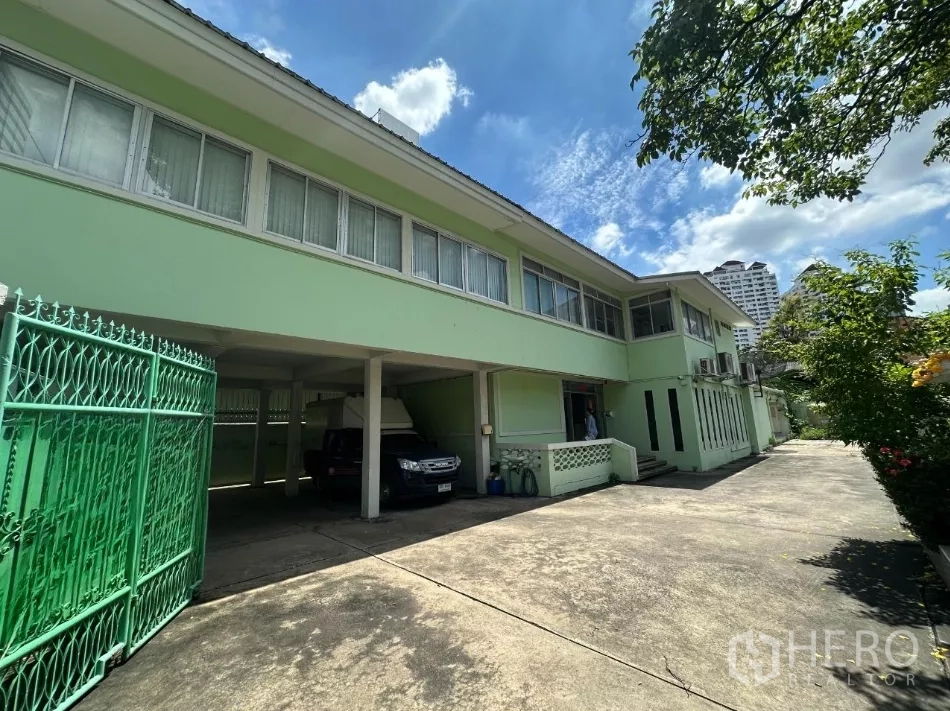 零售空间 出租在Watthana, Bangkok - 浅绿色两层独栋建筑，宽阔车道与有顶停车位。