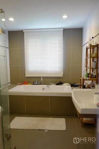 Detached House for sale in Pak Kret, Nonthaburi - Bathroom view of the large soaking tub beneath a window with blinds.