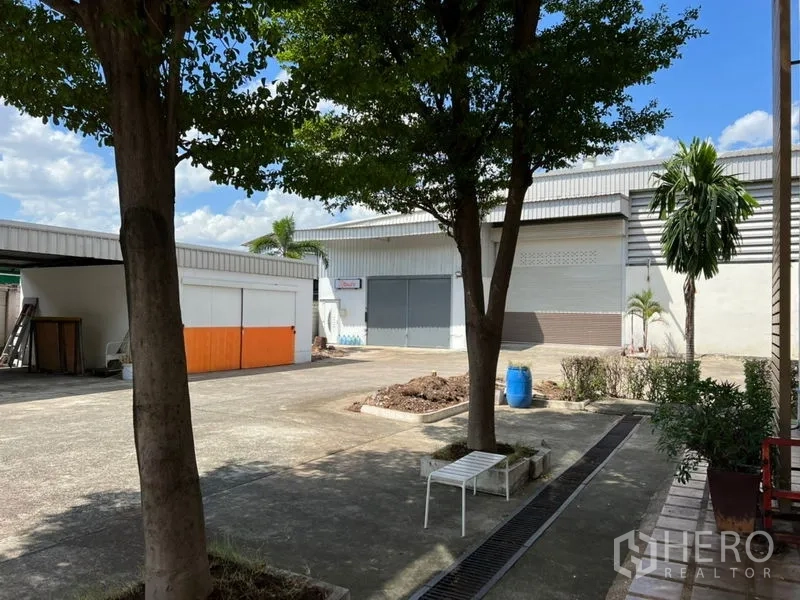 货栈 出租在Prawet, Bangkok - 中央庭院，遮荫大树、排水沟以及环绕的仓库建筑与装卸门