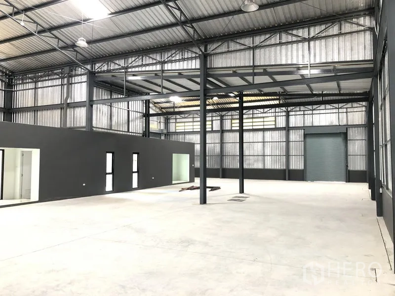 工厂 出租在Bang Yai, Nonthaburi - 仓库内部视角，高挑钢桁架、混凝土地面与内置办公室。