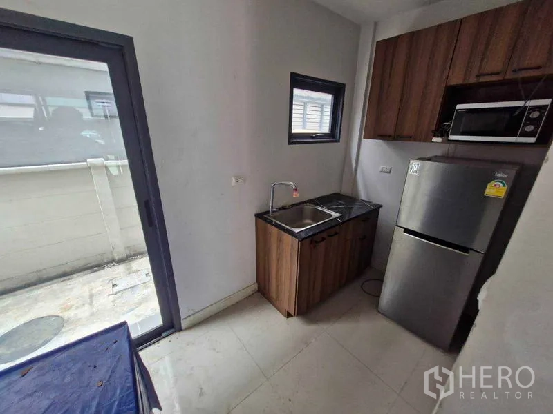 联排别墅 出售在Phra Pradaeng, Samut Prakan - 小巧厨房，木柜台、洗槽、冰箱、微波炉与推拉门