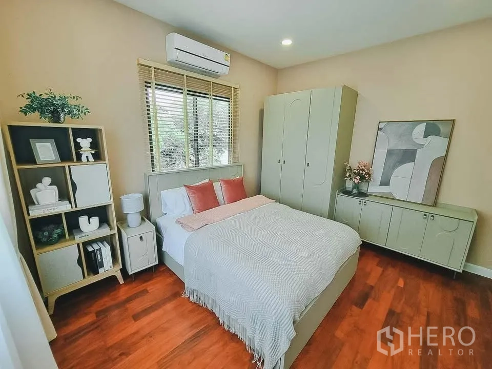 Detached House for rent or sale in Bang Phli, Samut Prakan - Warm-toned bedroom with air conditioner, bed, and matching storage cabinets.