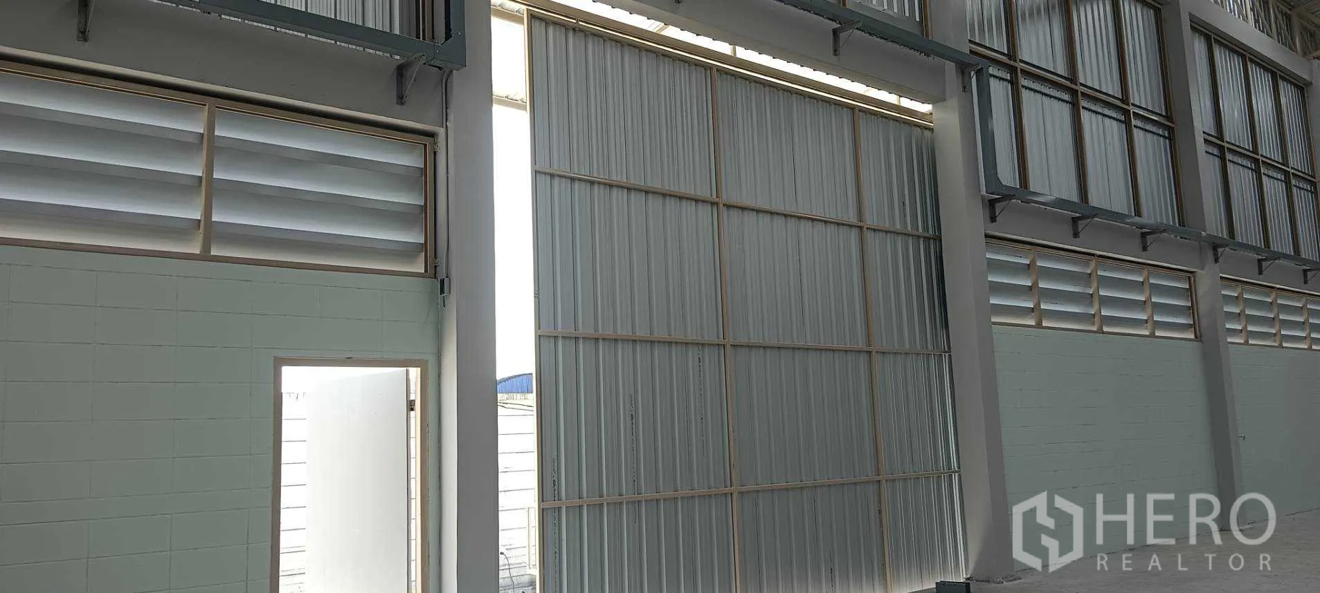 货栈 出租或出售在Lam Luk Ka, Pathum Thani - 仓库墙面的大型金属推拉门与通风百叶窗。
