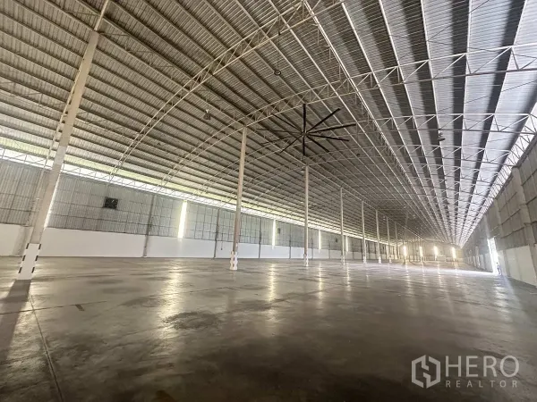 货栈 出租在Bang Pa-in, Phra Nakhon Si Ayutthaya - 长跨距仓库大厅，成排立柱与高挑屋顶，配工业吊扇。