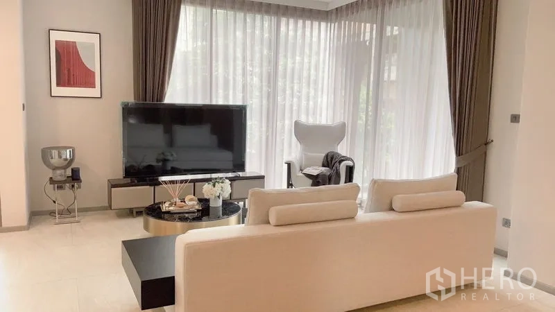 公寓 出租在Watthana, Bangkok - 明亮客厅，转角落地窗、电视柜、单人休闲椅与沙发。