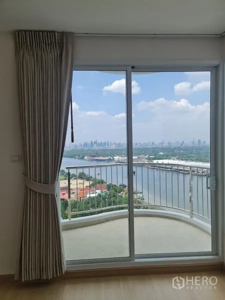 Condominium for sale in Yan Nawa, Bangkok - Bedroom with floor-to-ceiling sliding door to a balcony overlooking the river and city.