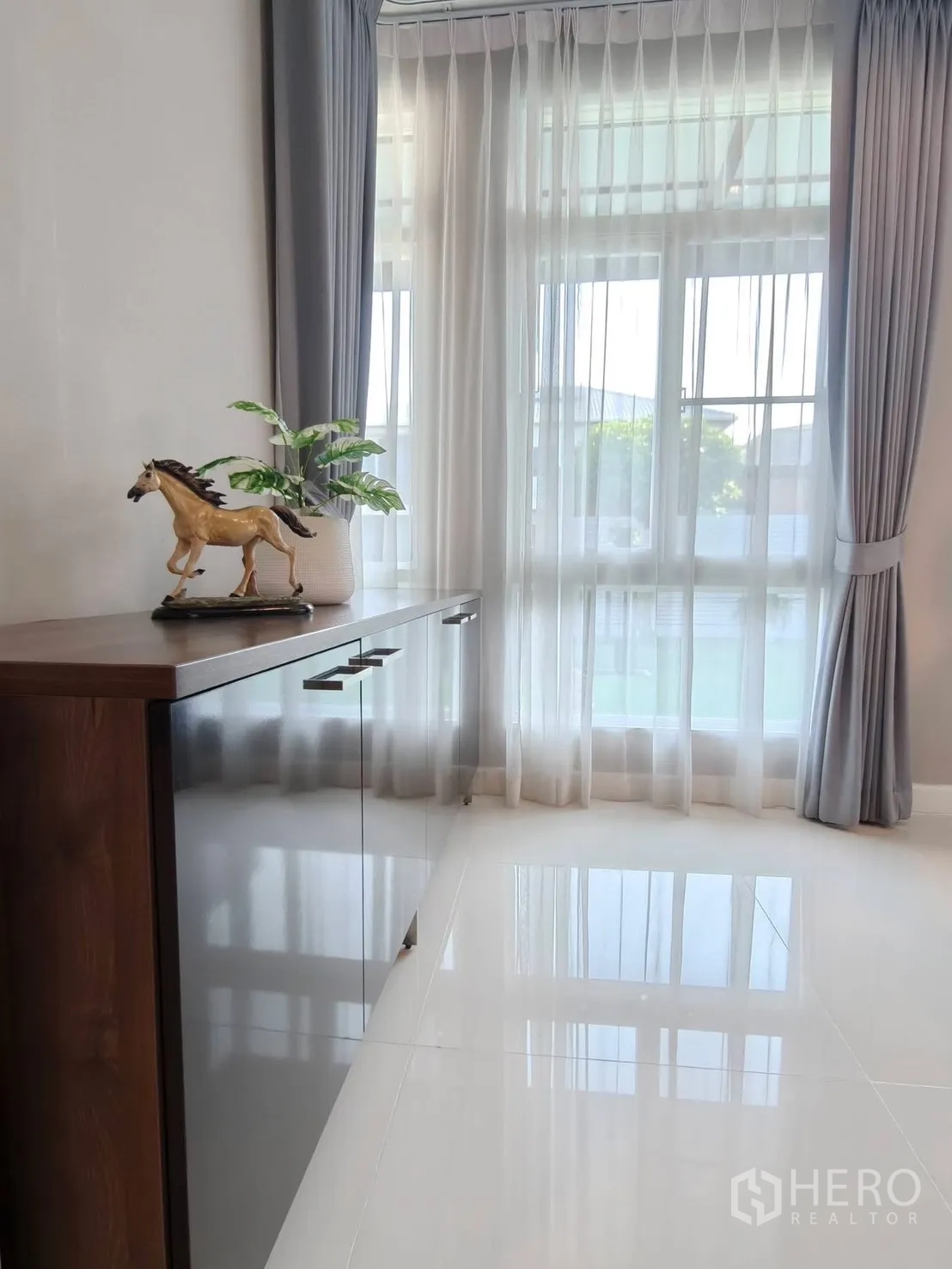 独栋房屋 for rent or sale in Bang Phli, Samut Prakan - 明亮角落，设矮柜与绿植，落地纱帘覆盖高窗。