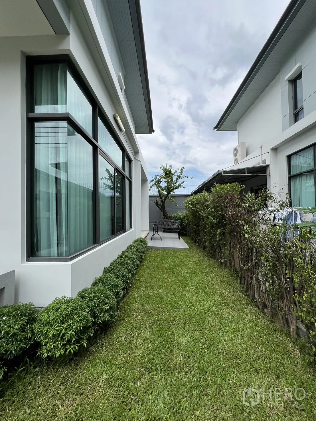 独立式住宅 出租在Bang Kapi, Bangkok - 侧院花园，绿色草坪与灌木，房屋凸窗相伴。