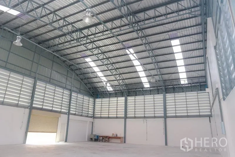 Factory for sale in Bang Pakong, Chachoengsao - Spacious warehouse interior with high arched steel roof, skylights, and louvered ventilation.