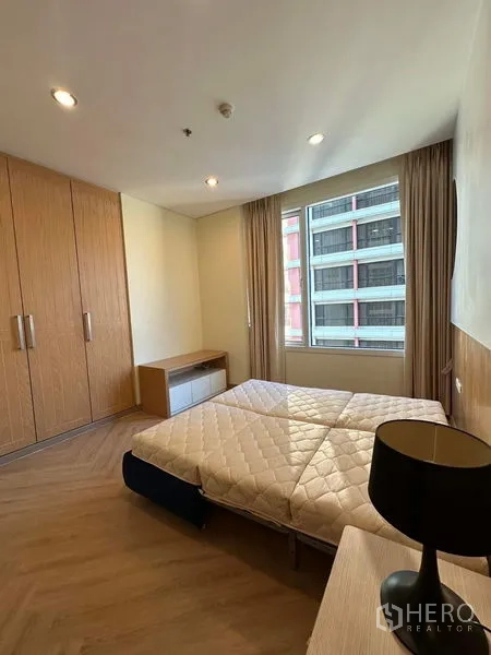 公寓 出租在Bang Rak, Bangkok - 卧室带大型衣柜、窗户与木地板。