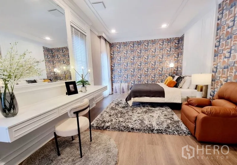 บ้าน ให้เช่าในSaphan Sung, Bangkok - ห้องนอนกว้าง โต๊ะเครื่องแป้งยาว ผนังวอลเปเปอร์ลวดลาย และเก้าอี้เอนกาย