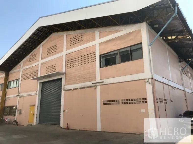 Warehouse for rent in Sam Phran, Nakhon Pathom - Front view of a high-clearance industrial warehouse with gable roof and large roller shutter loading door in Sam Phran.