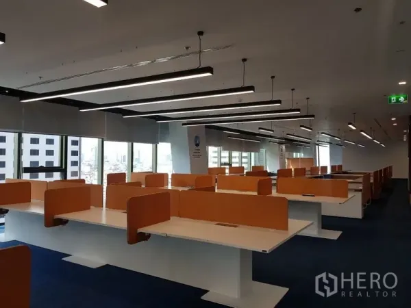 สำนักงาน ให้เช่าในHuai Khwang, Bangkok - แถวโต๊ะทำงานกว้างพร้อมฉากกั้นสีส้ม ใต้ไฟเส้น LED และหน้าต่างพาโนรามา