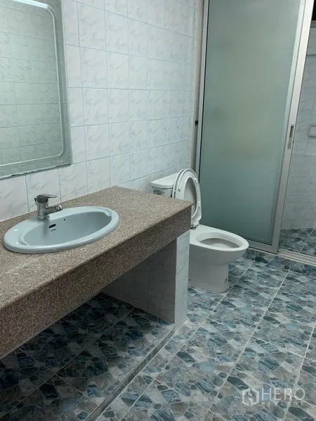 Condominium for rent in Sathon, Bangkok - Tiled bathroom featuring a wide vanity, basin, toilet and frosted glass shower enclosure.