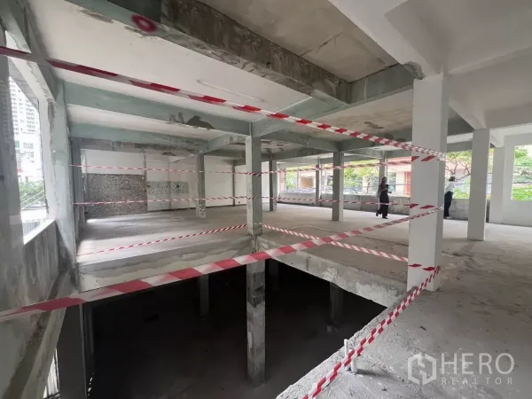 零售空间 出租在Bang Rak, Bangkok - 未完成楼层，楼梯洞口设警示带，裸露梁柱与周边窗户一览。