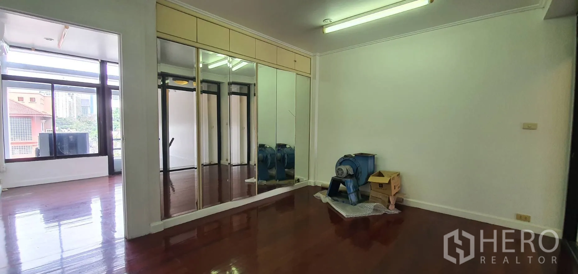 Home Office for rent in Khlong Toei, Bangkok - Room with mirrored built-in wardrobes and glossy wooden floors.