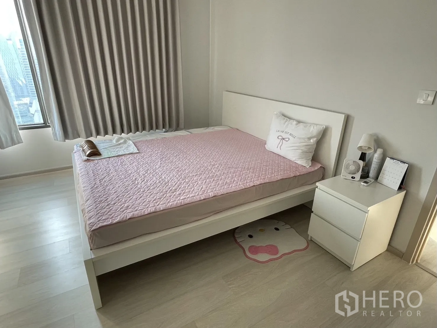 Condominium for rent in Pathum Wan, Bangkok - Second bedroom with pink bedspread, nightstand and city skyline through the window.