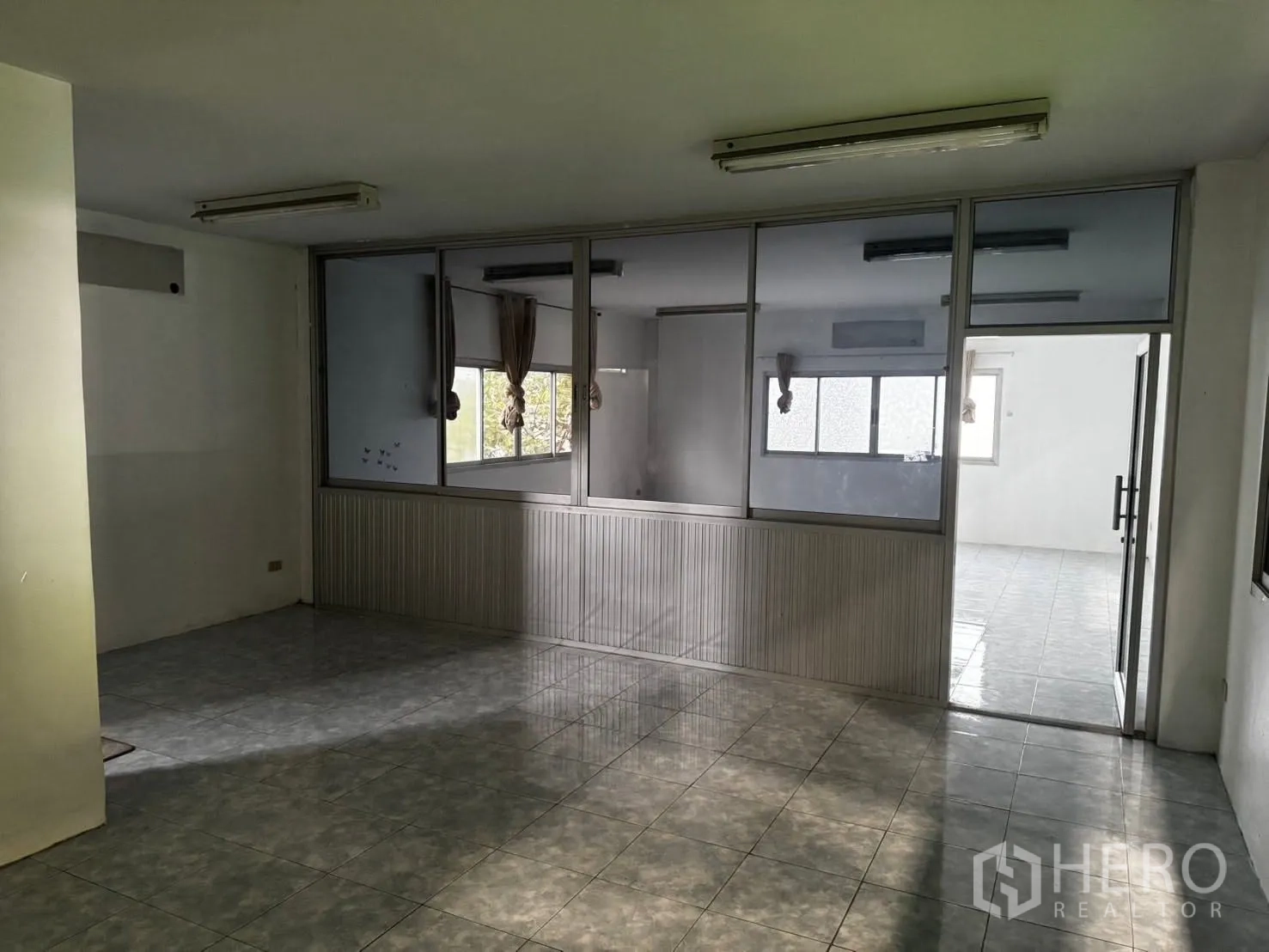 Factory for rent in Bang Phli, Samut Prakan - Glass-partitioned office area with tiled floors and fluorescent lighting inside the factory.